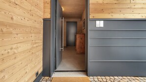 Un corridoio con rivestimenti in legno, una parete grigia e un pavimento piastrellato.