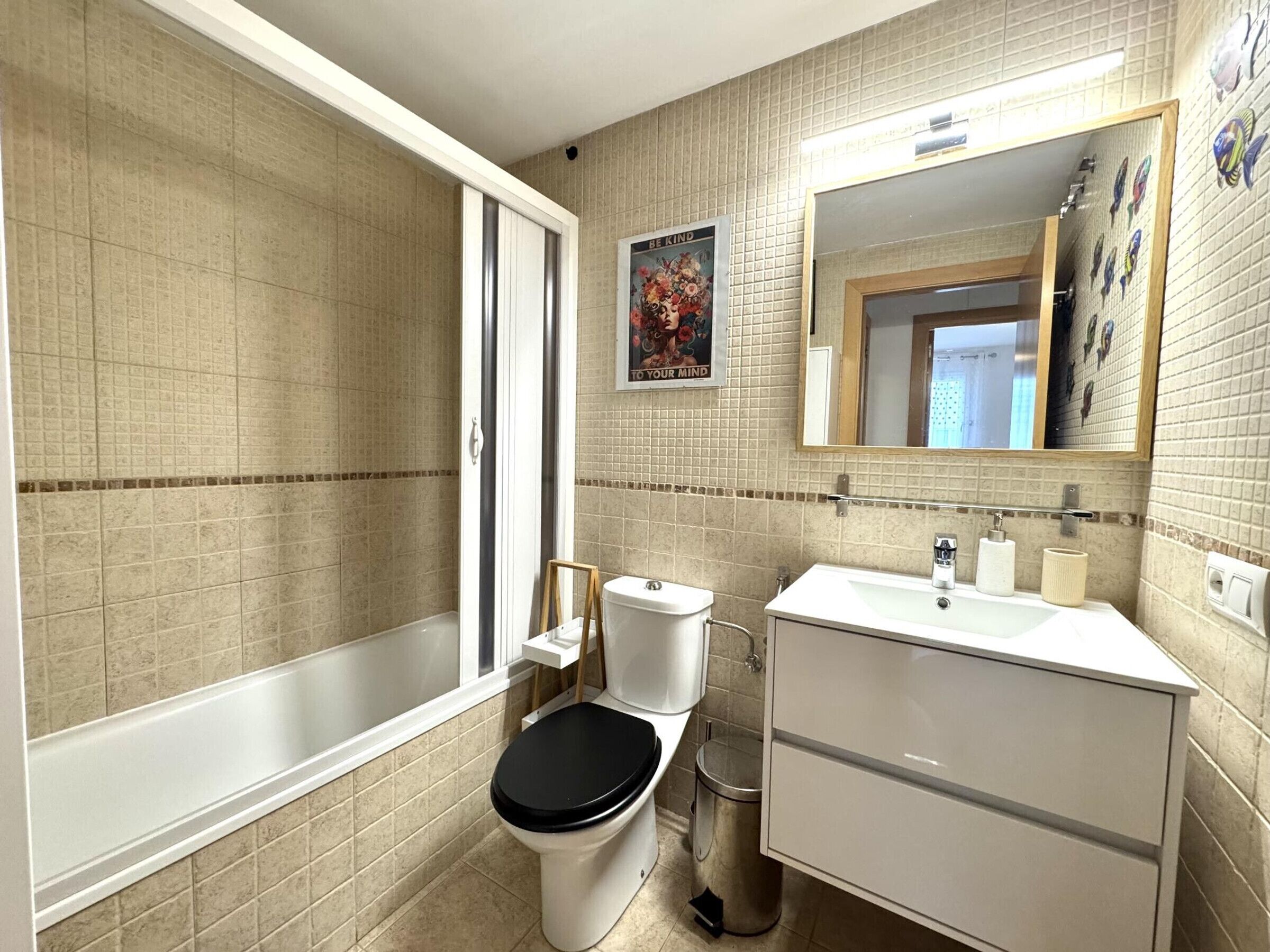 Un baño con bañera, inodoro, lavabo y espejo.