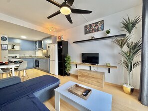 A modern living room with a sofa, TV, and a dining area with a table and chairs. - Cozy apartment in Roses with terrace and free Wi-Fi (Roses)