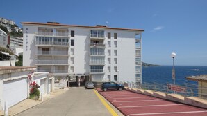 A multi-story building with balconies, a parking area with red lines, and a view of the sea. - 2-bedroom apartment with pool, parking, and WiFi near the beach in Roses (Roses)