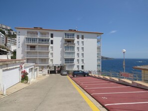 A multi-story building with balconies, a parking area with red lines, and a view of the sea. - 2-bedroom apartment with pool, parking, and WiFi near the beach in Roses (Roses)