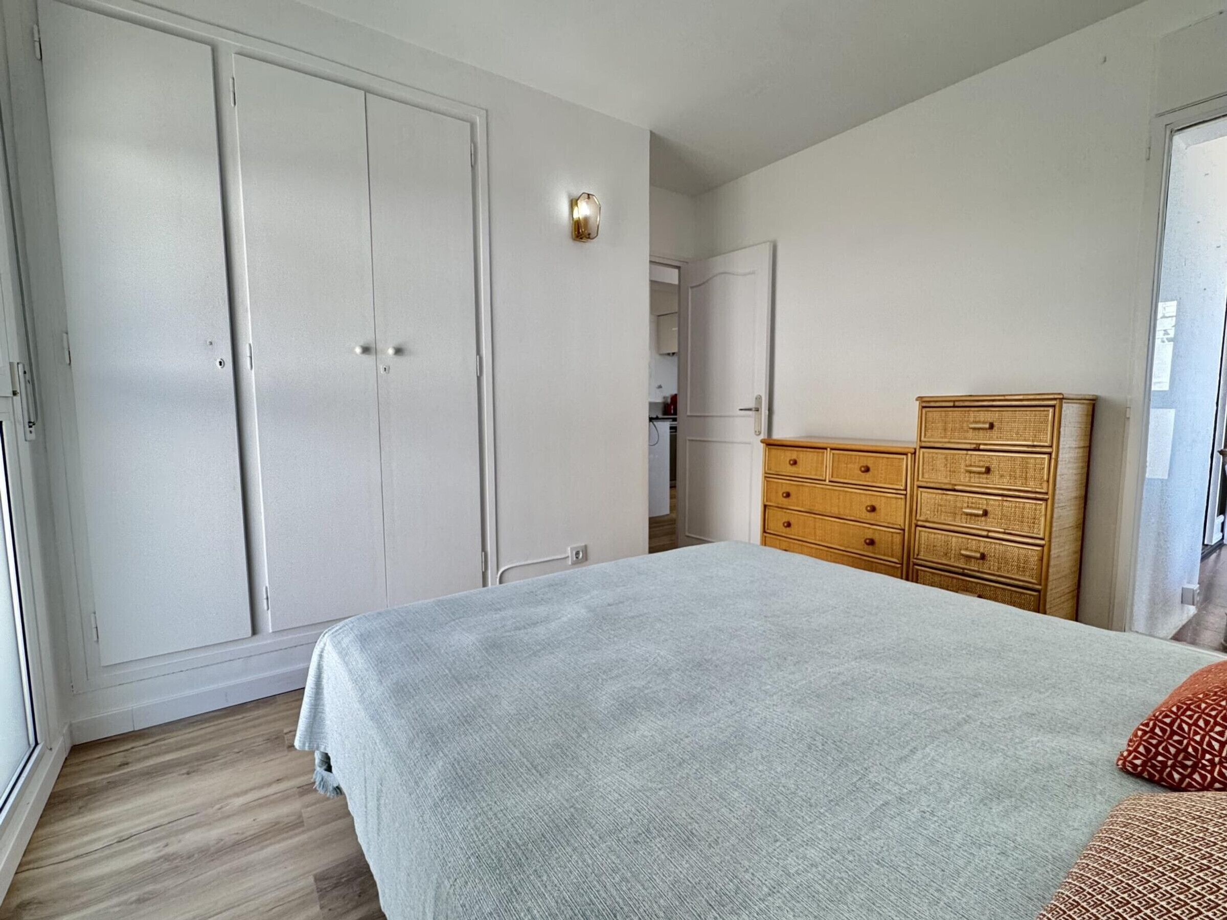 A bedroom with a bed, a wardrobe, a dresser, and a door leading to a bathroom.
