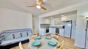 A compact living space with a dining area, kitchenette, and a ceiling fan. - 2-bedroom apartment with pool, parking, and WiFi near the beach in Roses (Roses)