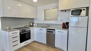 A modern kitchen with white cabinetry, a built-in microwave, a coffee maker, and a dishwasher. - 2-bedroom apartment with pool, parking, and WiFi near the beach in Roses (Roses)