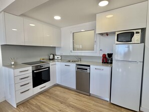 A modern kitchen with white cabinetry, a built-in microwave, a coffee maker, and a dishwasher. - 2-bedroom apartment with pool, parking, and WiFi near the beach in Roses (Roses)