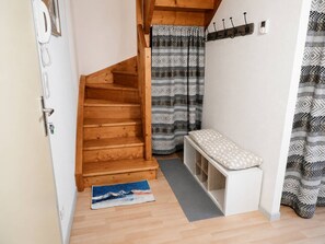 Eine Holztreppe führt zu einem Schlafzimmer mit einer Schlafkoje, einer Sitzbank und einem gemusterten Vorhang.