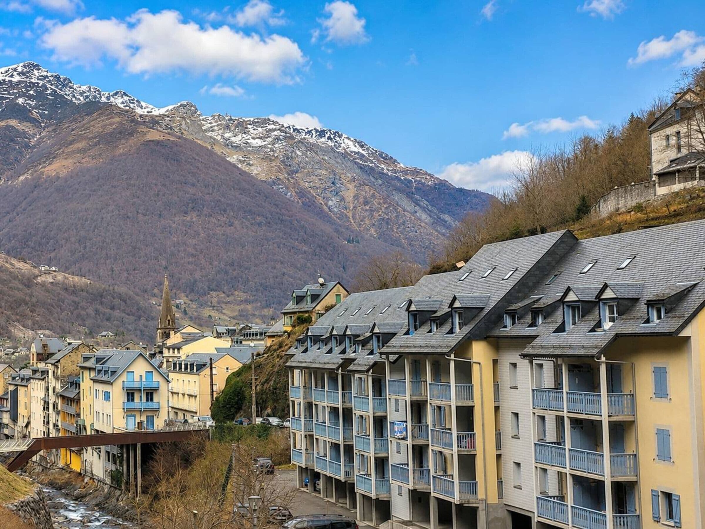 A mountain town with residential buildings, a church, and a view of snow-capped mountains.