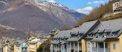 A mountain town with residential buildings, a church, and a view of snow-capped mountains.