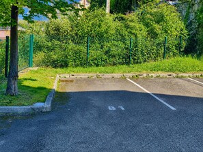 A parking lot with a tree and a green fence. - Duplex with parking - 5 guests (Cauterets)