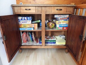 A wooden cabinet with two doors, each containing various board games and books. - Duplex with parking - 5 guests (Cauterets)