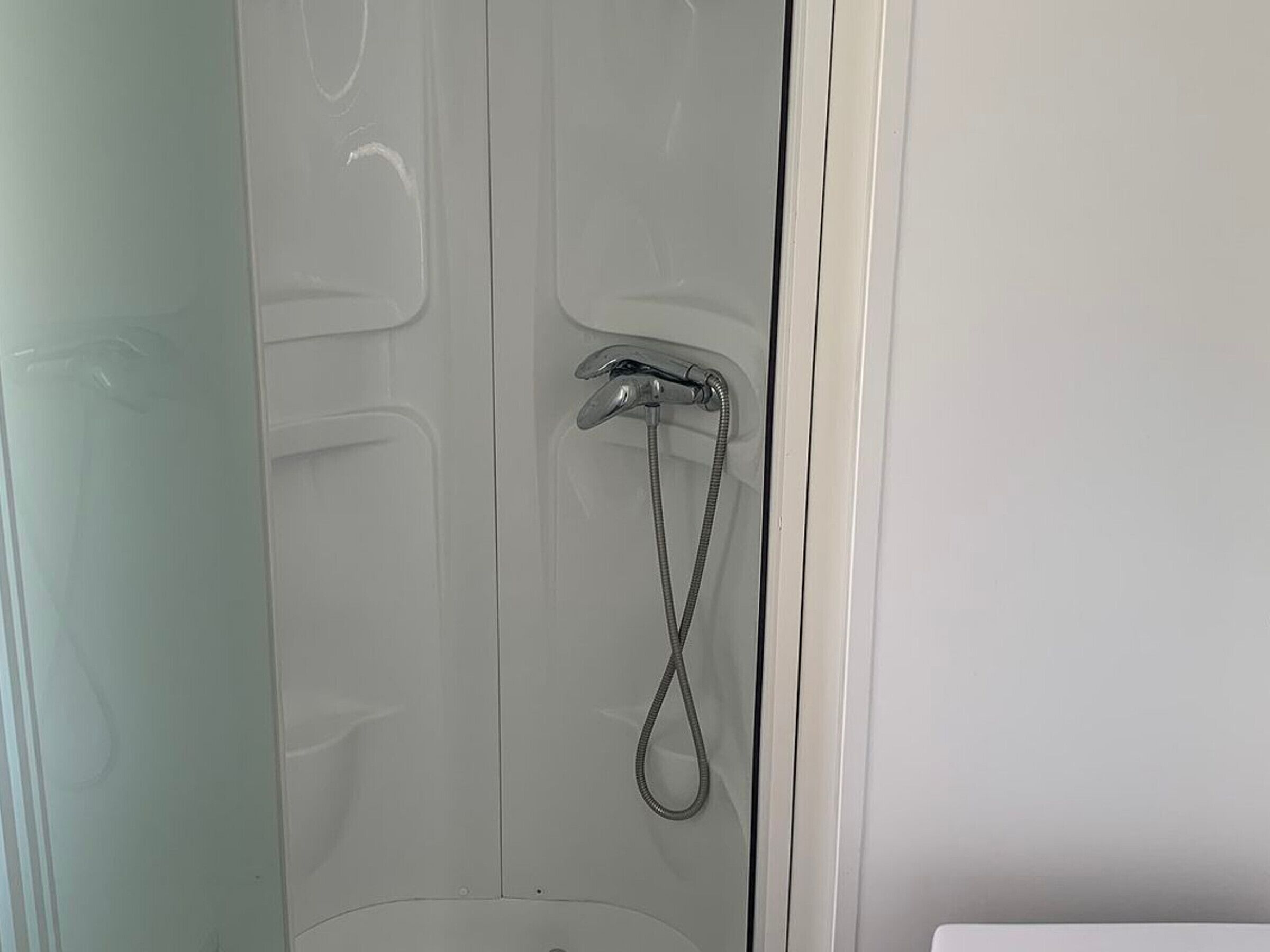Ducha con cabezal de ducha de mano y grifo de pared fijo.