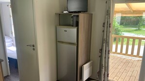 A compact room with a bed, a small kitchenette with a refrigerator and a television, and a sliding glass door leading to an outdoor deck. - Mobile home with terrace - 6 guests (Thiviers)