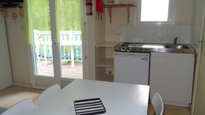 A compact kitchen with a sink, stove, and a small window. - Cozy chalet with terrace - 6 guests (Thiviers)