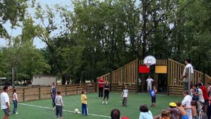 A basketball court with a wooden fence, a basketball hoop, and spectators.
