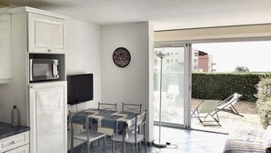 A compact kitchen with a microwave, a flat-screen TV, and a dining table with chairs. - Charming T2 sea view - 4 guests (Le CAP D'AGDE)