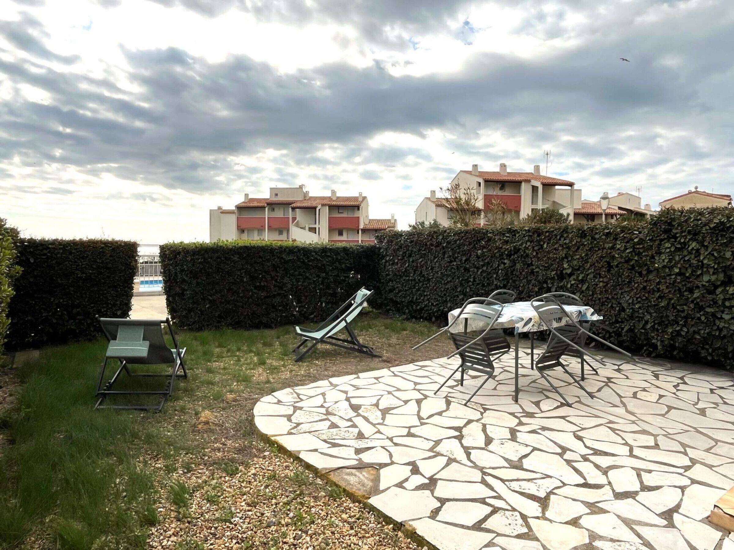 A courtyard with a mosaic-tiled patio, outdoor furniture, and a view of residential buildings in the background.