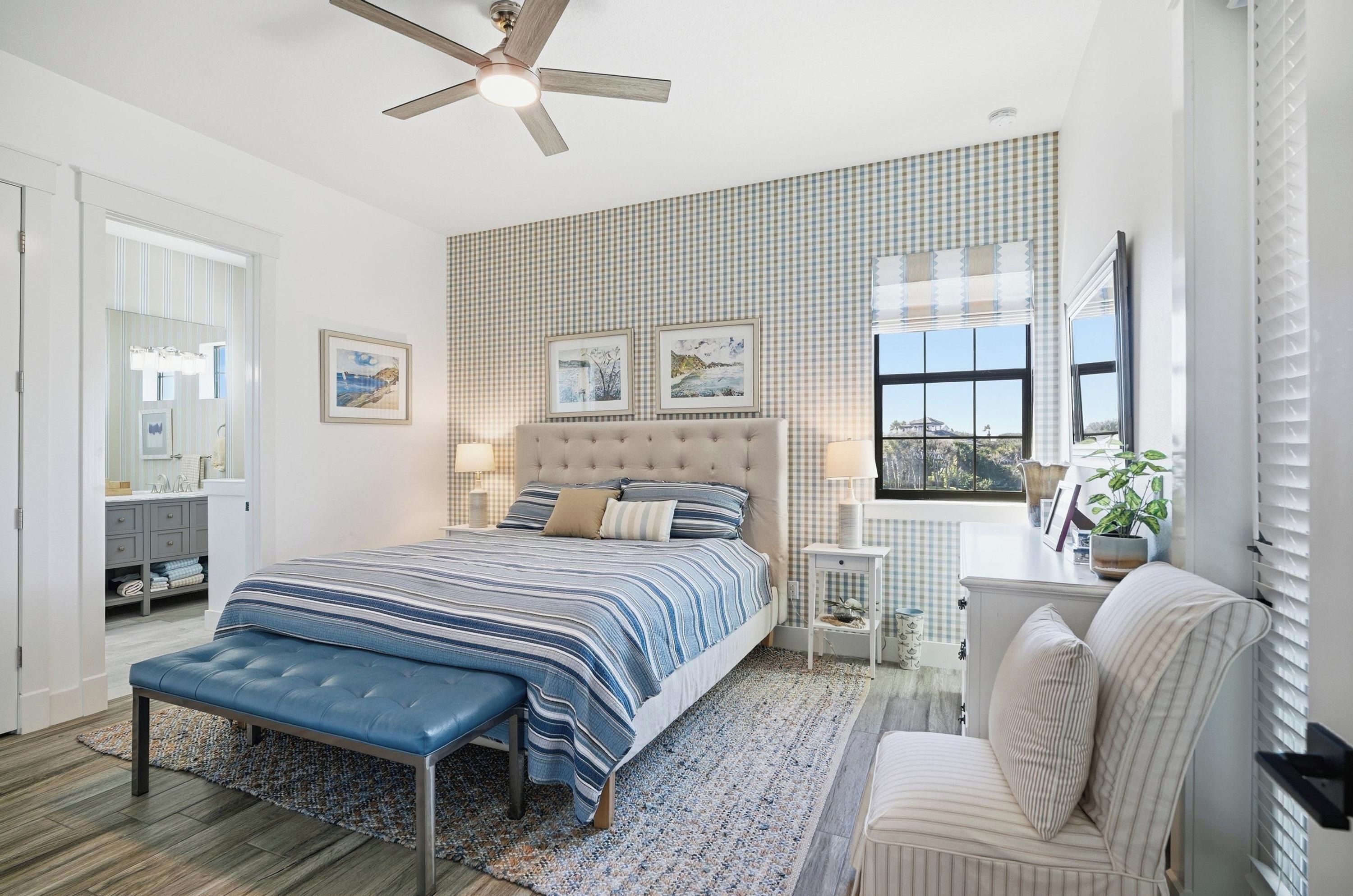 A bedroom with a large bed, a ceiling fan, a window with blinds, and a view of the outdoors.