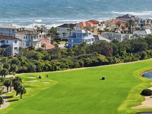Campo de golf con vista al océano y edificios residenciales.
