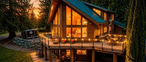 Une cabane en rondins dotée d’une terrasse, d’un espace salon extérieur et d’un coin barbecue.