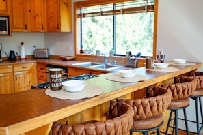 Una cocina con armarios de madera, una encimera larga y una ventana con vistas a la vegetación.