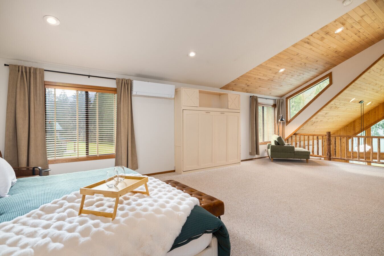 Ein Schlafzimmer mit einem Bett, einer hölzernen Bank, einem Sofa und einem großen Fenster.