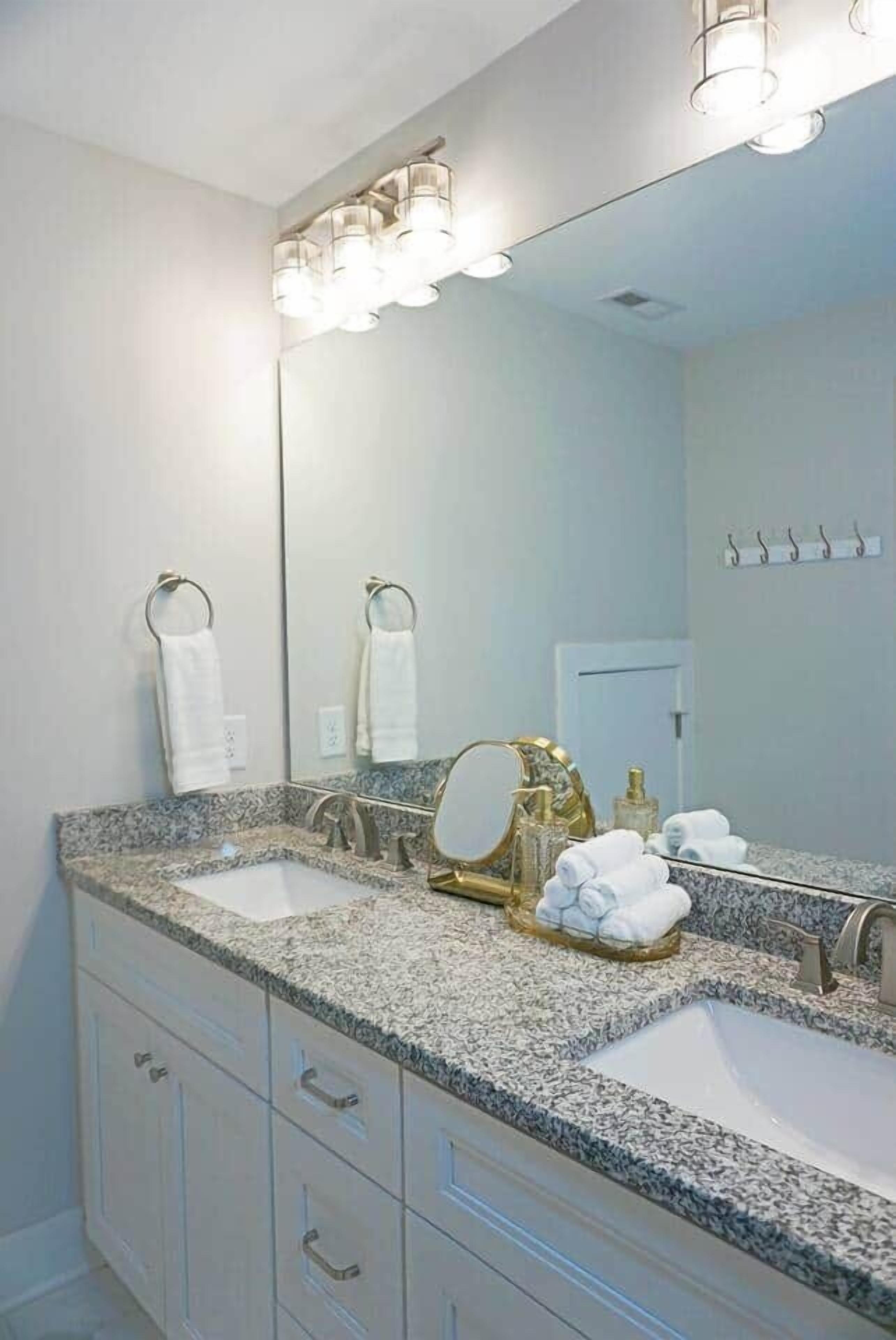 A bathroom with two sinks, a large mirror, and a towel rack.