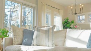 A living room with a white sofa, large windows, and a chandelier. - Cozy Cottage 4BR. in the Heart of Huntersville (Huntersville)