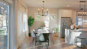 A modern kitchen with a dining area, large windows, and a central chandelier. - Cozy Cottage 4BR. in the Heart of Huntersville (Huntersville)