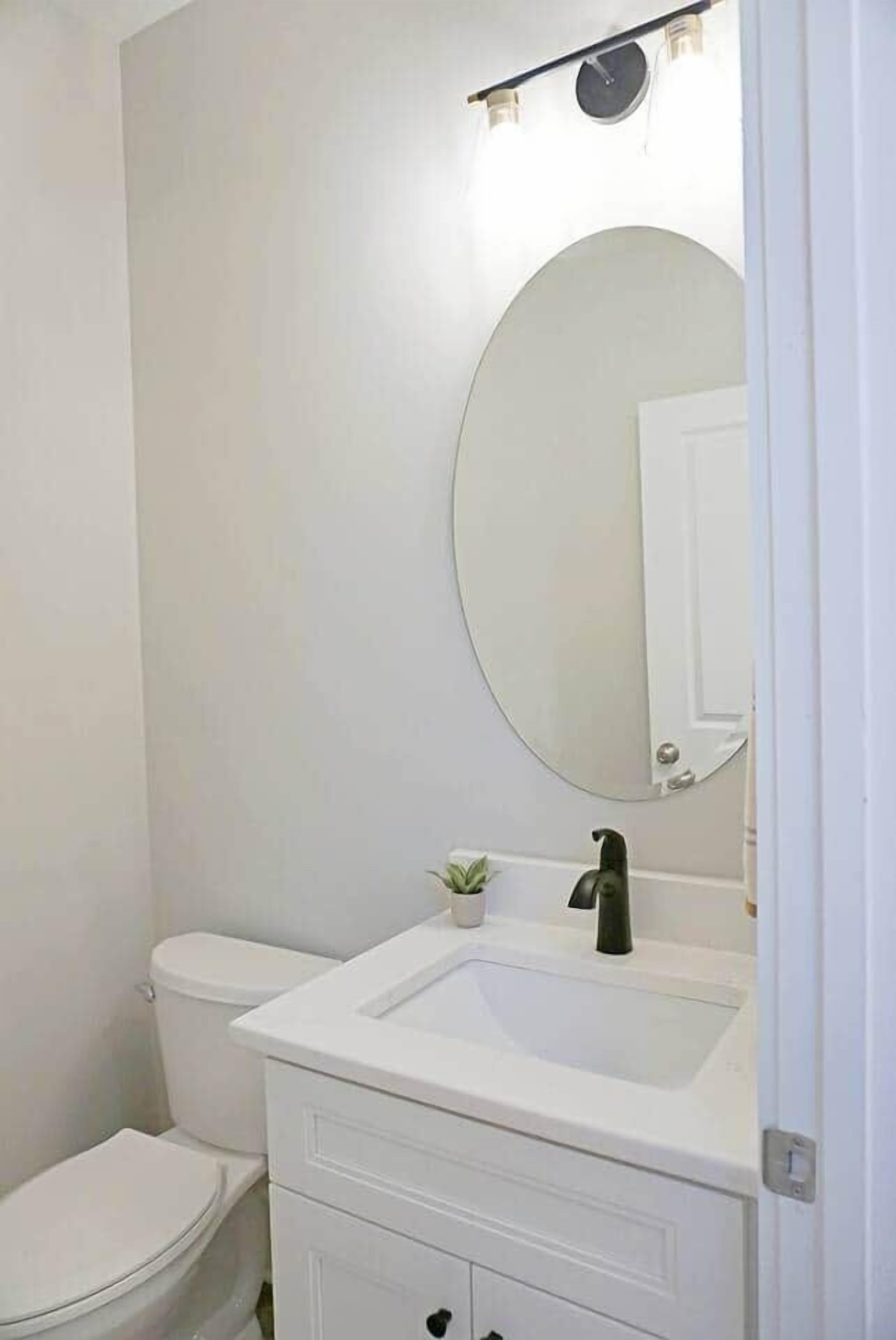 A bathroom with a white toilet, a white sink, and a mirror above the sink.
