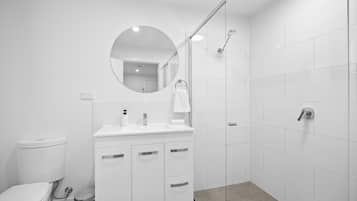 Een moderne badkamer met toilet, wastafel en douche.