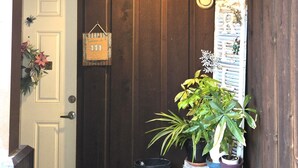 Une porte en bois avec une plaque indiquant les numéros « 111-113 » et une petite enseigne accrochée au mur.