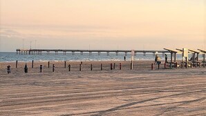 Une plage avec une jetée qui s’avance dans l’eau, des parasols de plage et un poste de surveillance pour les sauveteurs.