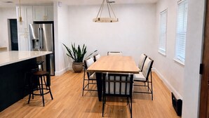 A modern kitchen with a large island, stainless steel appliances, and a wooden dining table with chairs. - Skyline View Home w/ Office - Minutes From Culver, LAX, Santa Monica & SOFI (Los Angeles)