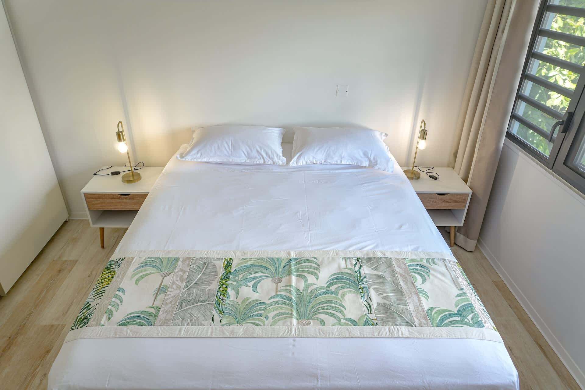 Une chambre à coucher avec un lit, deux tables de chevet et une fenêtre.