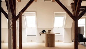 Een ruime loft met hoge plafonds, zichtbare houten balken en grote ramen.