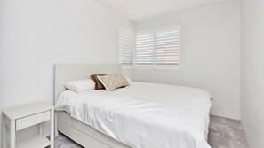 A minimalist bedroom with a single bed, a nightstand, and a window with blinds. - The Helm 3, 22 Voyager Cl - stunning water views, Wi-Fi (Nelson Bay)