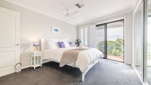 A bedroom with a bed, bedside tables, a ceiling fan, and a view of the outdoors. - Seaview on Government, 58B Government Rd - Water Views, Air Con, Wi-Fi (Nelson Bay)