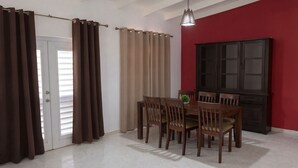 Un comedor con mesa y sillas, un armario y cortinas.