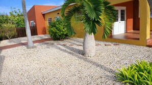 Una casa con entrada de grava, palmeras y una valla de madera.