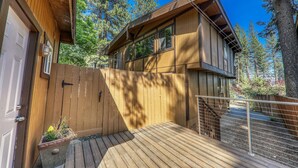 Una cabaña de madera moderna con terraza, rodeada de árboles altos.