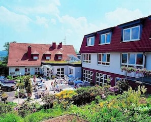 A hotel with a red-tiled roof, multiple windows, and a garden area with outdoor seating. - Fasanerie (Marburg)