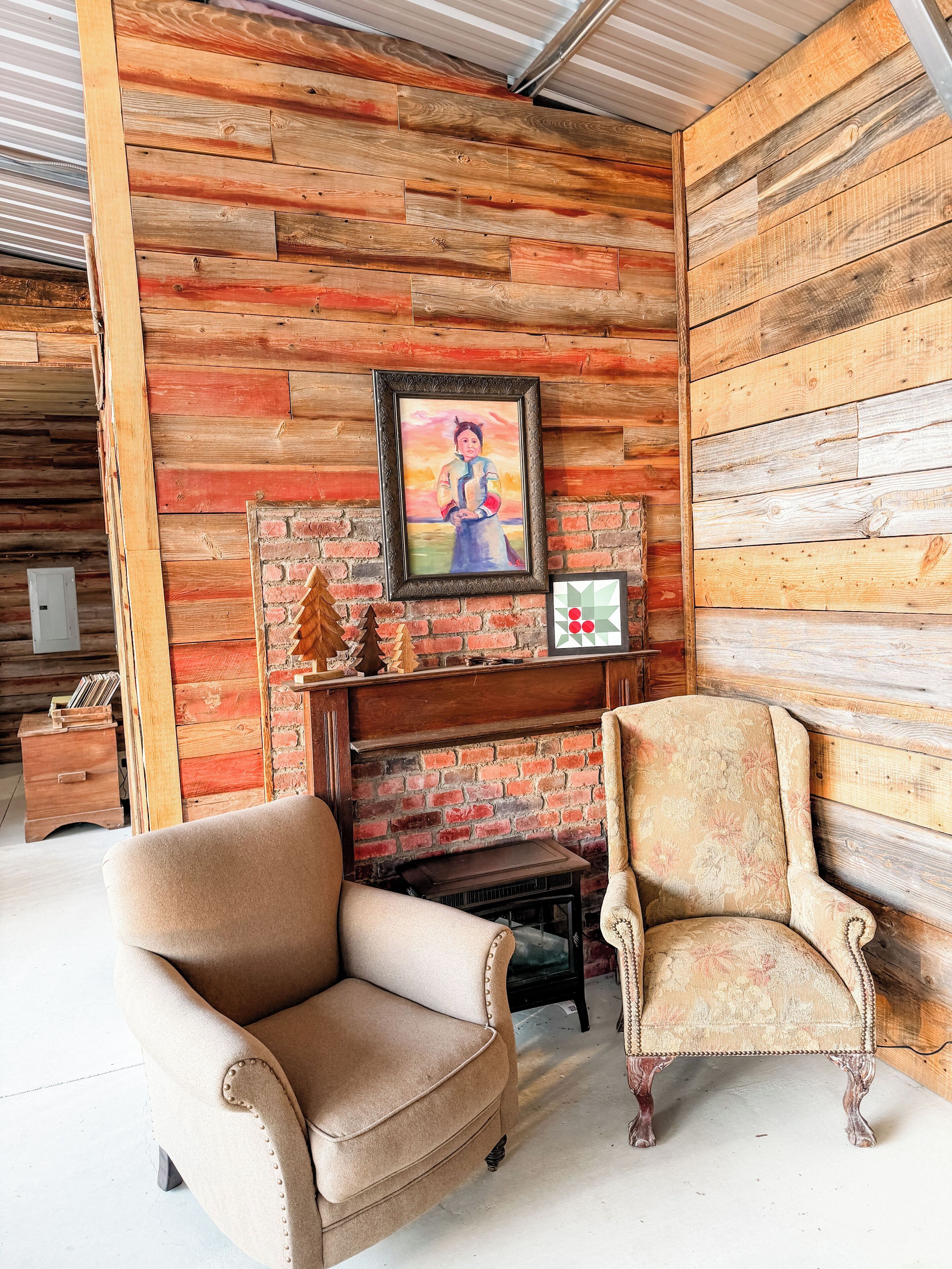Une pièce rustique avec des murs en bois, une cheminée et deux fauteuils rembourrés.