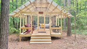 A wooden cabin with a porch, a bed, and a seating area.