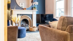 A living room with a fireplace, a television, and comfortable seating. - Stunning 2BD Townhouse in Cheltenham (Cheltenham)