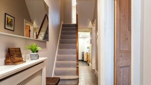 A staircase leading to a second floor, a wooden bench, a potted plant, and a door. - Stunning 2BD Townhouse in Cheltenham (Cheltenham)