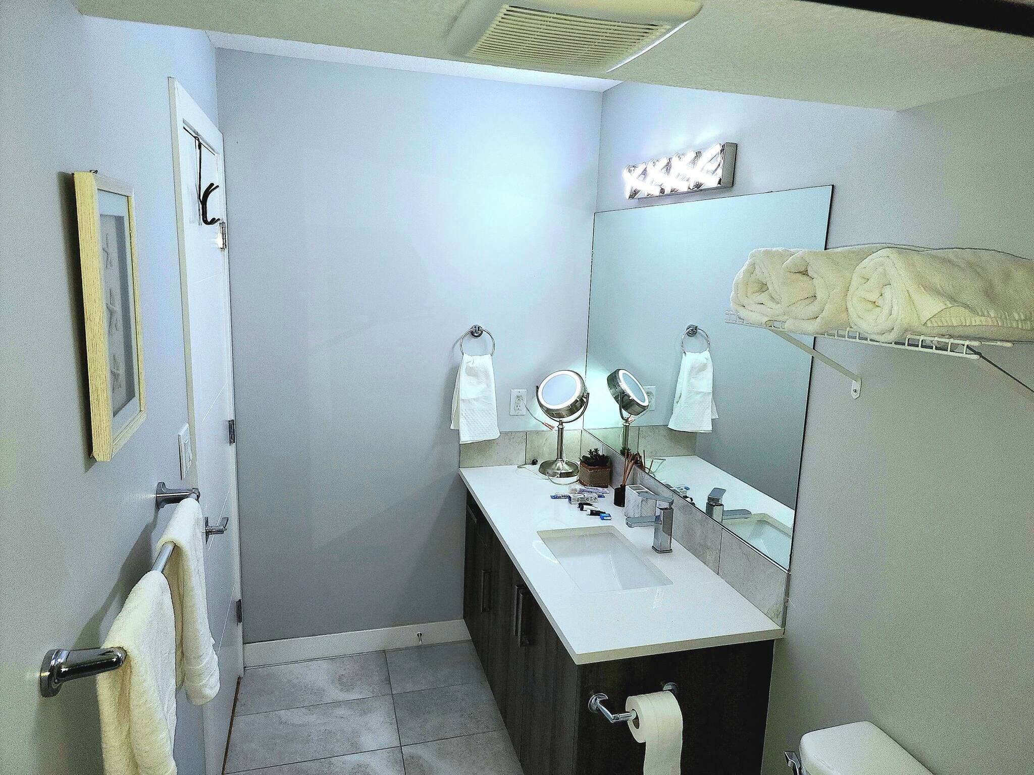A bathroom with a sink, two mirrors, a toilet, and a towel rack.