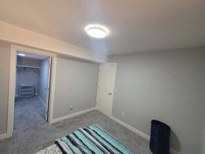 A small, empty room with a closet, a door, and a carpeted floor. - Luxurious Home Away From Home With Aircon (Airdrie)