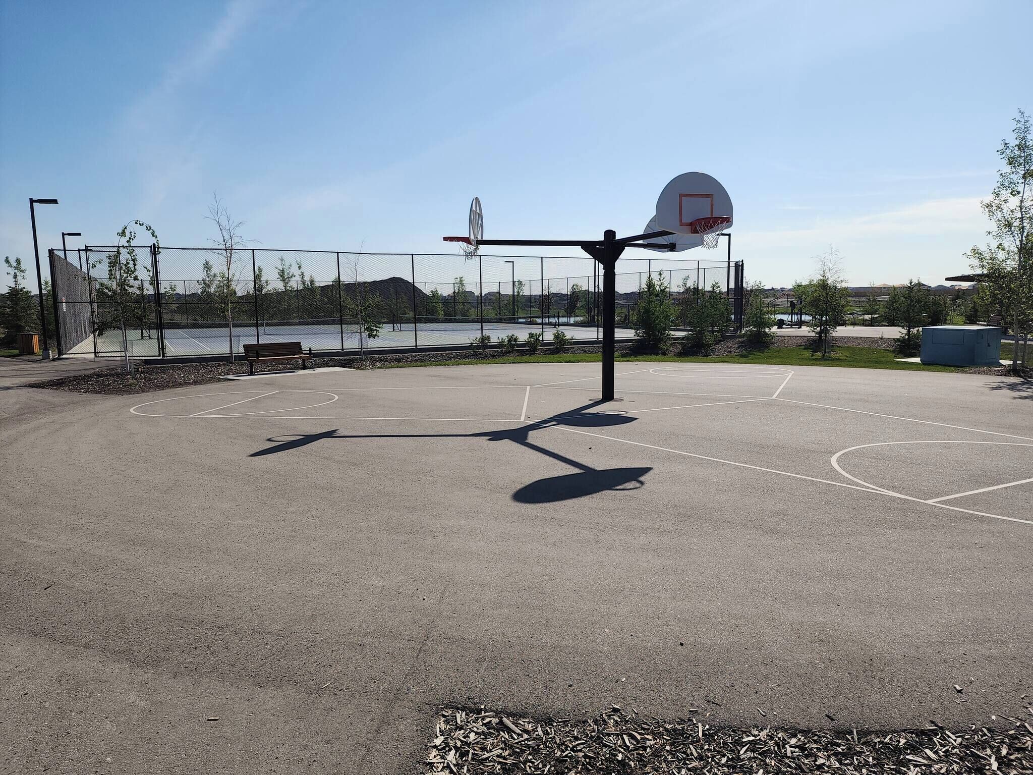 Una cancha de baloncesto al aire libre con un aro, una banca y vistas a un lago.
