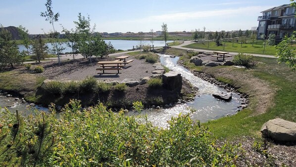 A riverside park with picnic tables and a walking path.