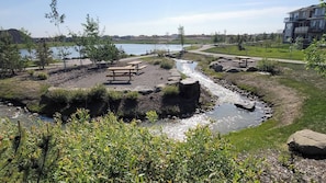 Un parque junto al río con mesas de picnic y un sendero para caminar.